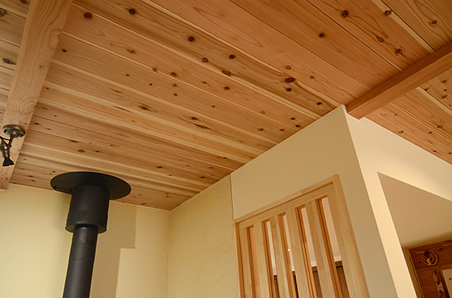 薪ストーブの煙突が無垢材の天井にキレイに配置